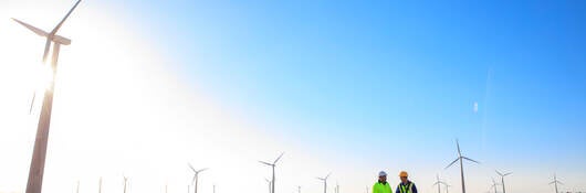 Engineers standing next to a wind turbine at a windfarm