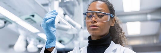 Chemist adding a sample to a solution in conical flask