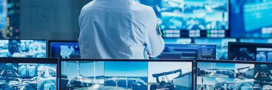 A control room security officer looking at several monitors