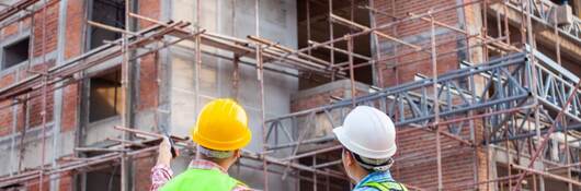 Civil engineers and construction workers at work on construction site considering how to measure embodied carbon of a new building.