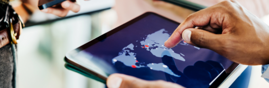 Business professionals collaborate using a digital tablet displaying a global map, indicating international reach and strategic planning