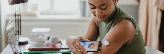 A person checking blood glucose monitoring device on her phone