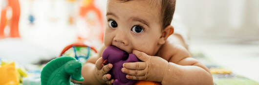 A baby with a toy in his mouth