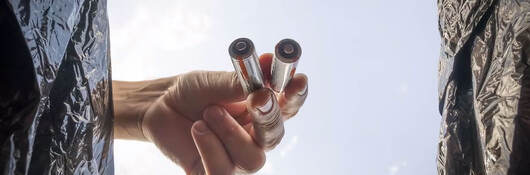 A person dropping old batteries in a bin