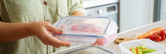 woman storing vegetables in glass container