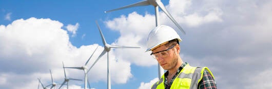 An engineer working on a tablet at a wind farm