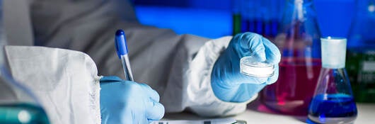 A chemist writing on a paper on a clipboard