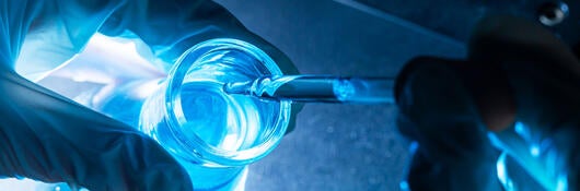 A lab technician pipetting liquid into a flask