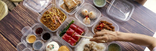 People selecting food from plastic food containers