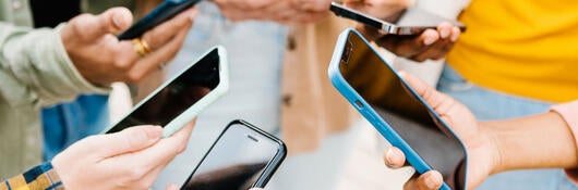 Group of people standing in a circle holding out their mobile phones
