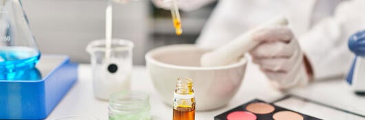 A lab technician using a dropper in a cosmetics laboratory