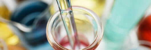 Pipette in laboratory flask containing transition metal salts