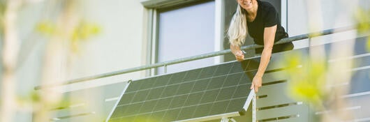 A person using a fold-up solar panel on their deck wall