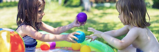 two children playing with toys in a wading pool