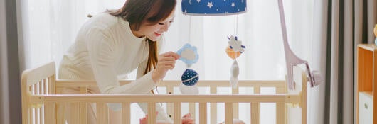 A parent leaning over a child in a crib