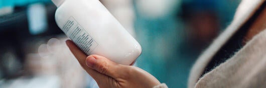 Person reading the label on a bottle of hand soap while shopping in a store