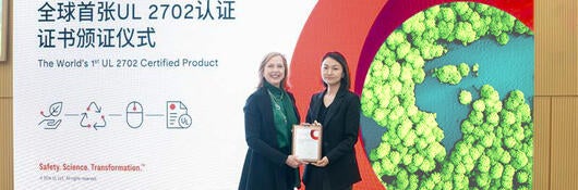Two women in front of an illuminated panel announcing Razer's gaming equipment earning recycled content achievement from UL Solutions