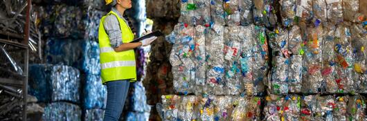 Worker looking at stacks of recycled materials.