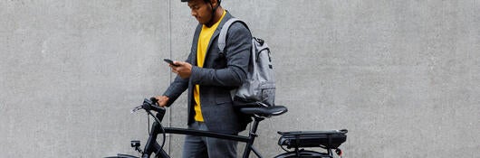 Person standing next to an electric bike looking at a phone.
