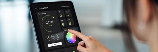 Person using a tablet device to control smart home technologies.