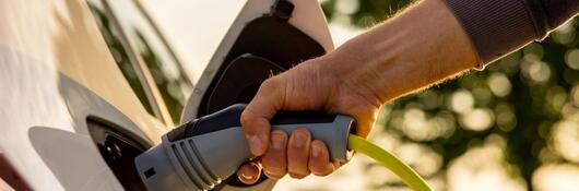 Person plugging a charger into an electric vehicle.