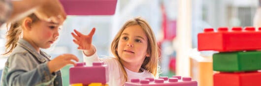 Two young children playing with foam building blocks outdoors 