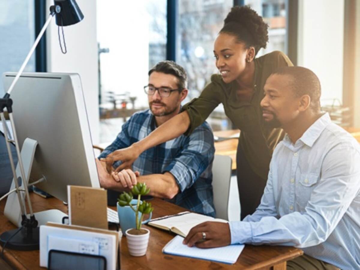 Three business people working around a computer in the office