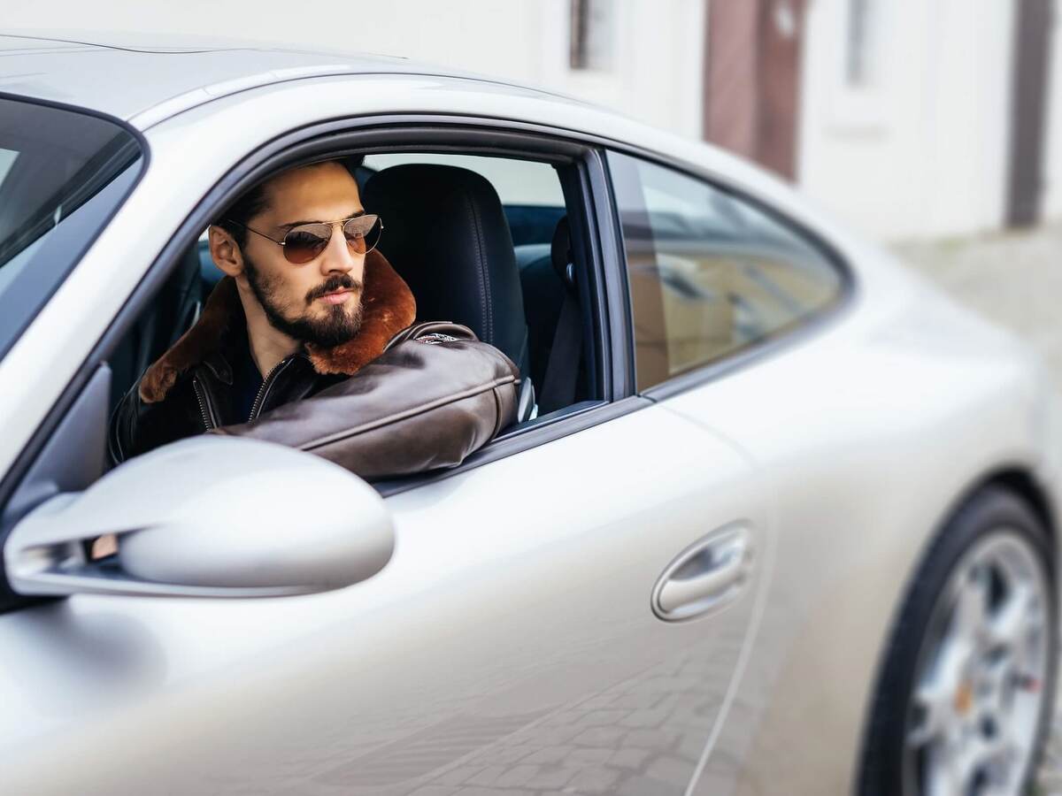 Handsome man sitting in a silver Porche