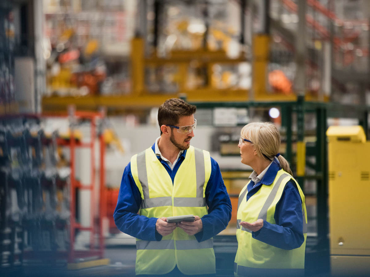 Workers collaborating in a warehouse with a tablet