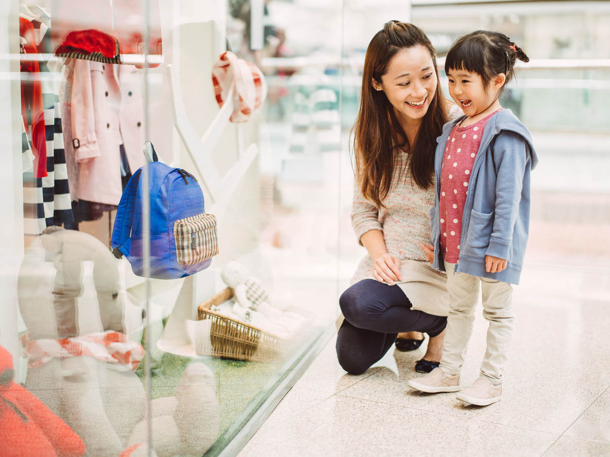 A mother and her daughter look at a clothing store window display in China.