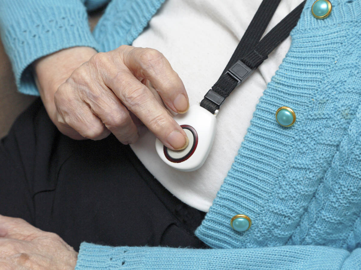 Elderly woman demonstrating call button worn on neck strap