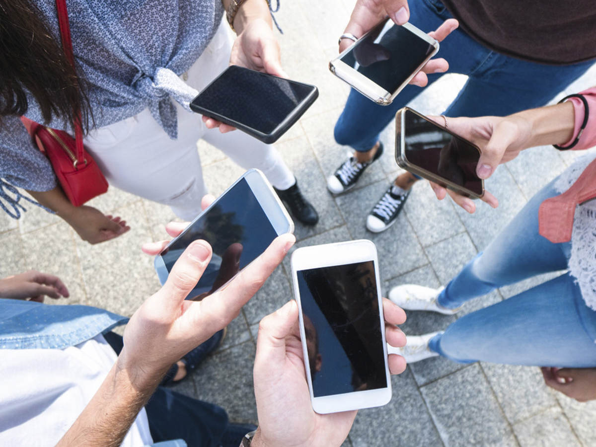 A group of young adults scrolling through their cell phones. 