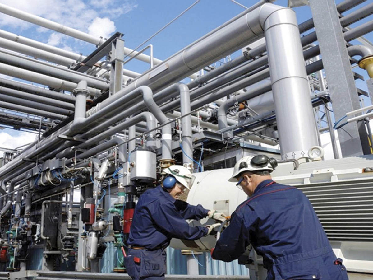 Two workers at refinery working next to pipes