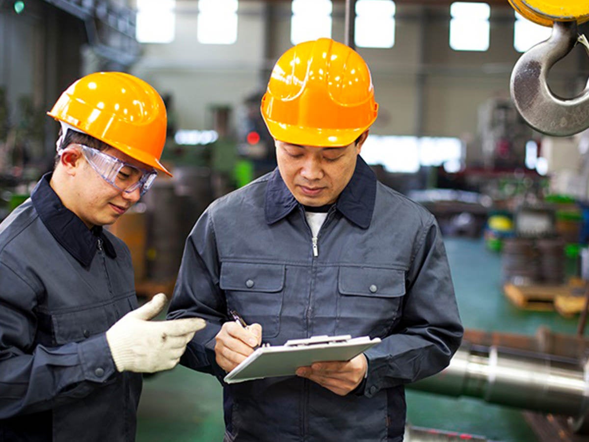 Two men in hard hats writing on a clipboard