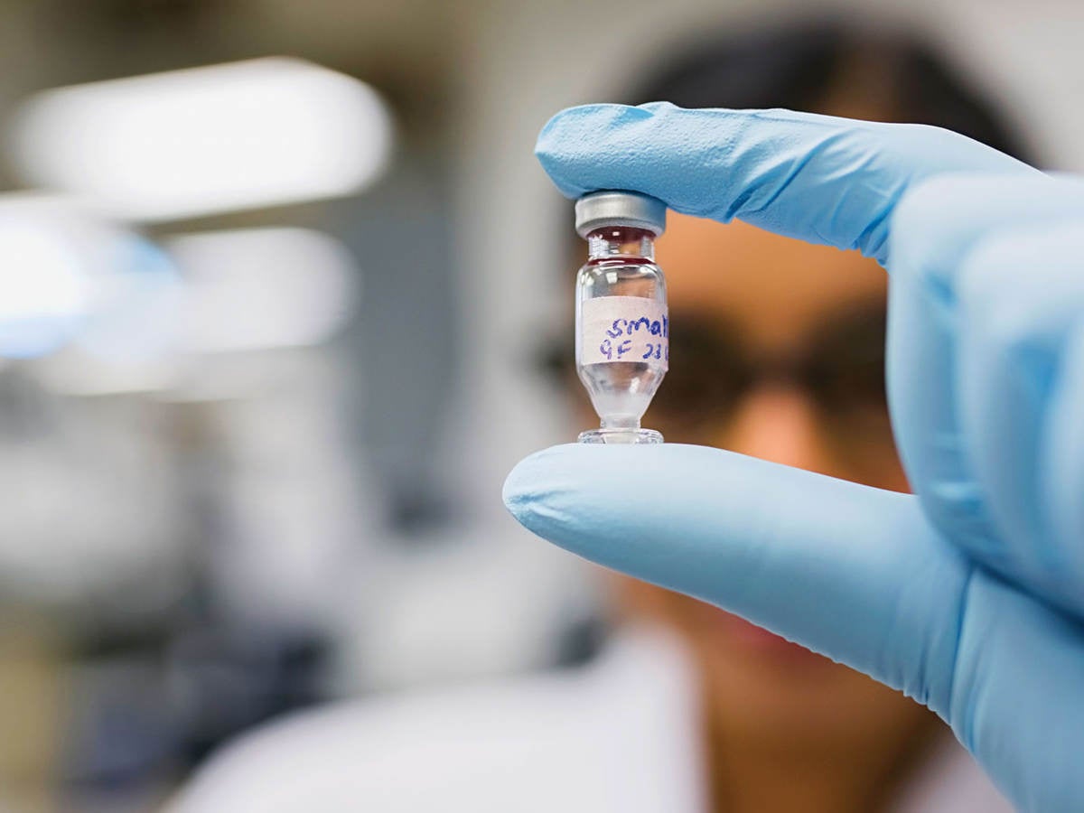 Gloved hand holding a chemical vial in a laboratory setting