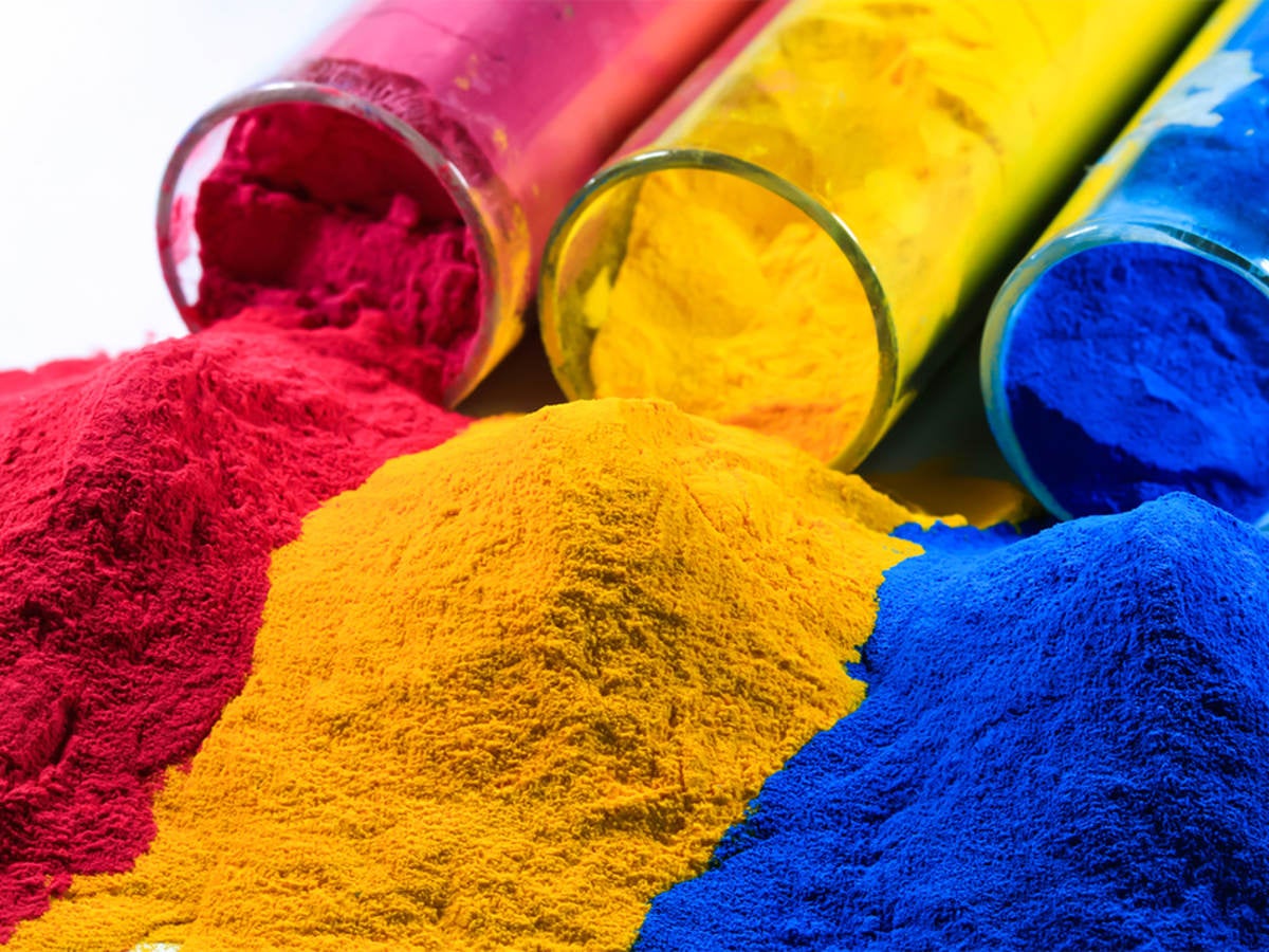 Magenta, yellow and cyan powders spill out of glass jars next to each other.