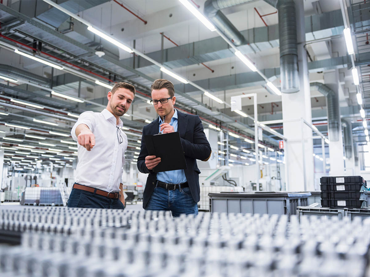 Two men consulting over pallets of plastic products