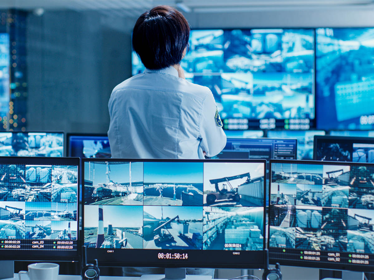 Person standing in a control room looking at security video feeds