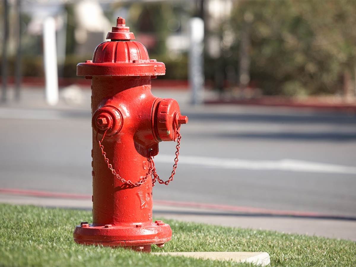 A bright red fire hydrant along a road.