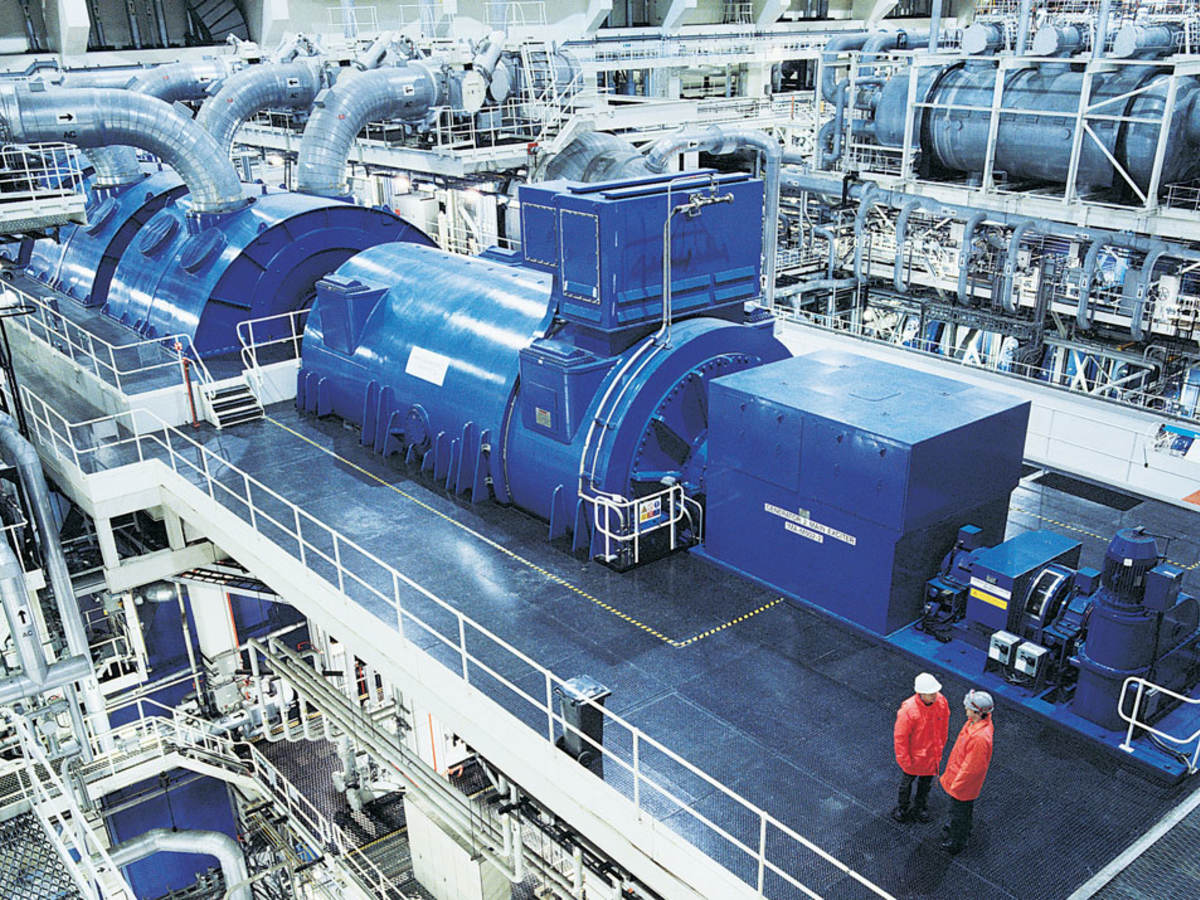 Two workers near an industrial generator in a warehouse setting