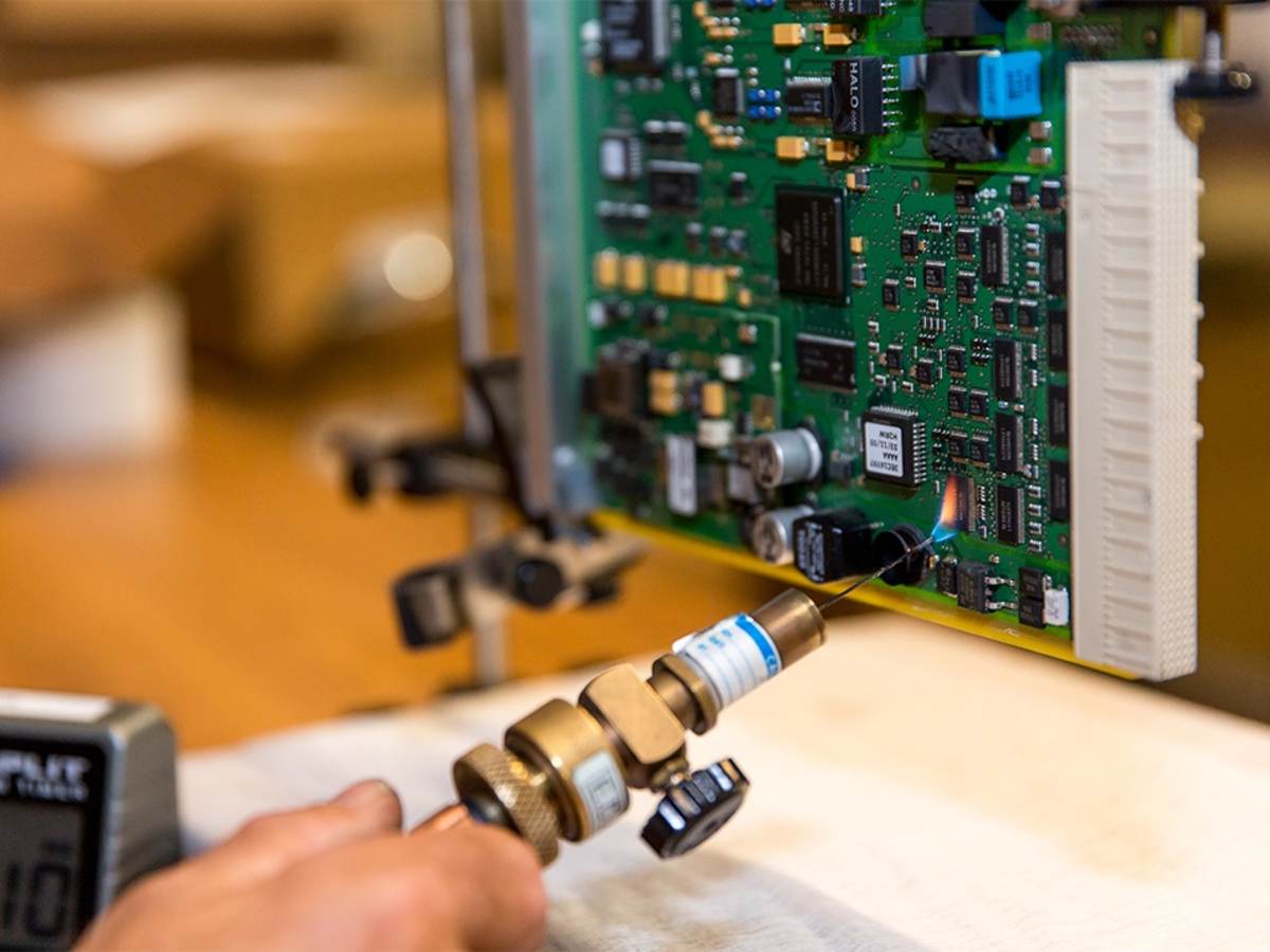 A worker fusing together parts of a motherboard. 