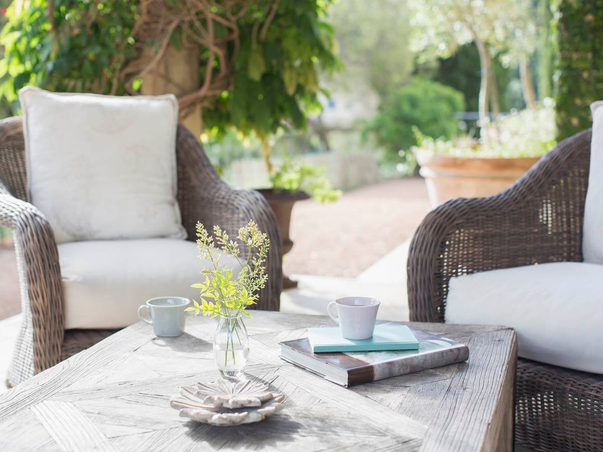 An vignette of two brown wicker chairs solidly resting on an outdoor patio.