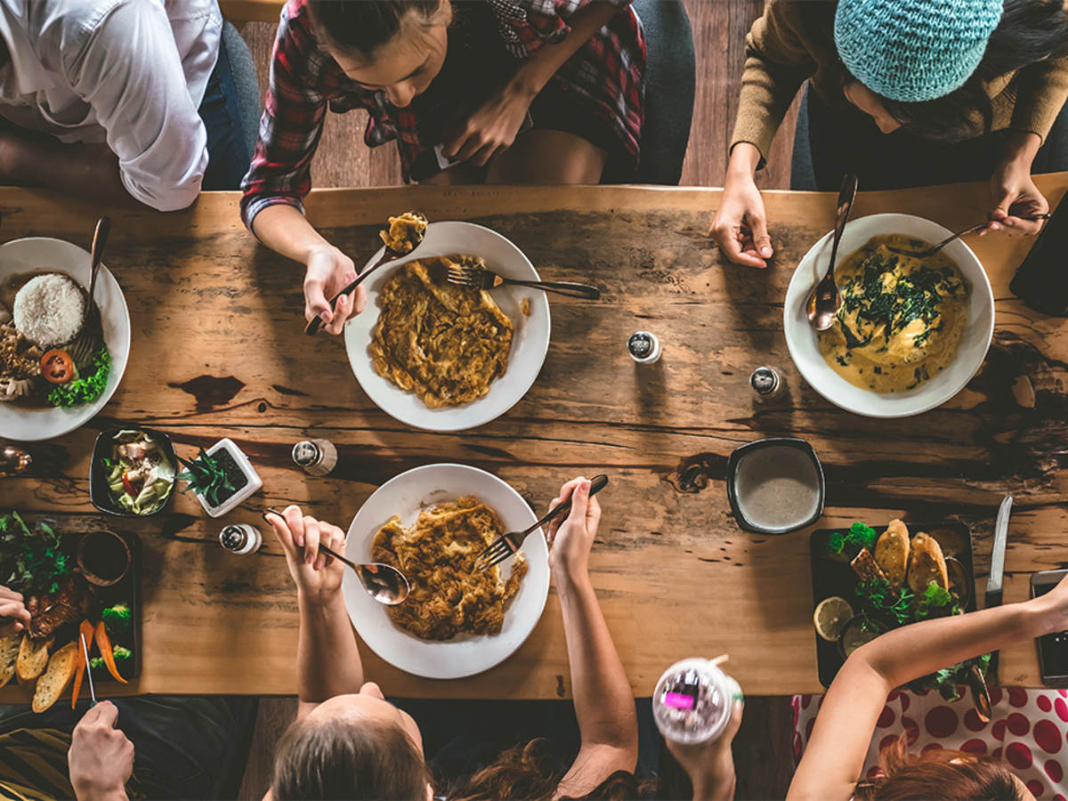 Bird’s-eye view of young people eating around a dinner table