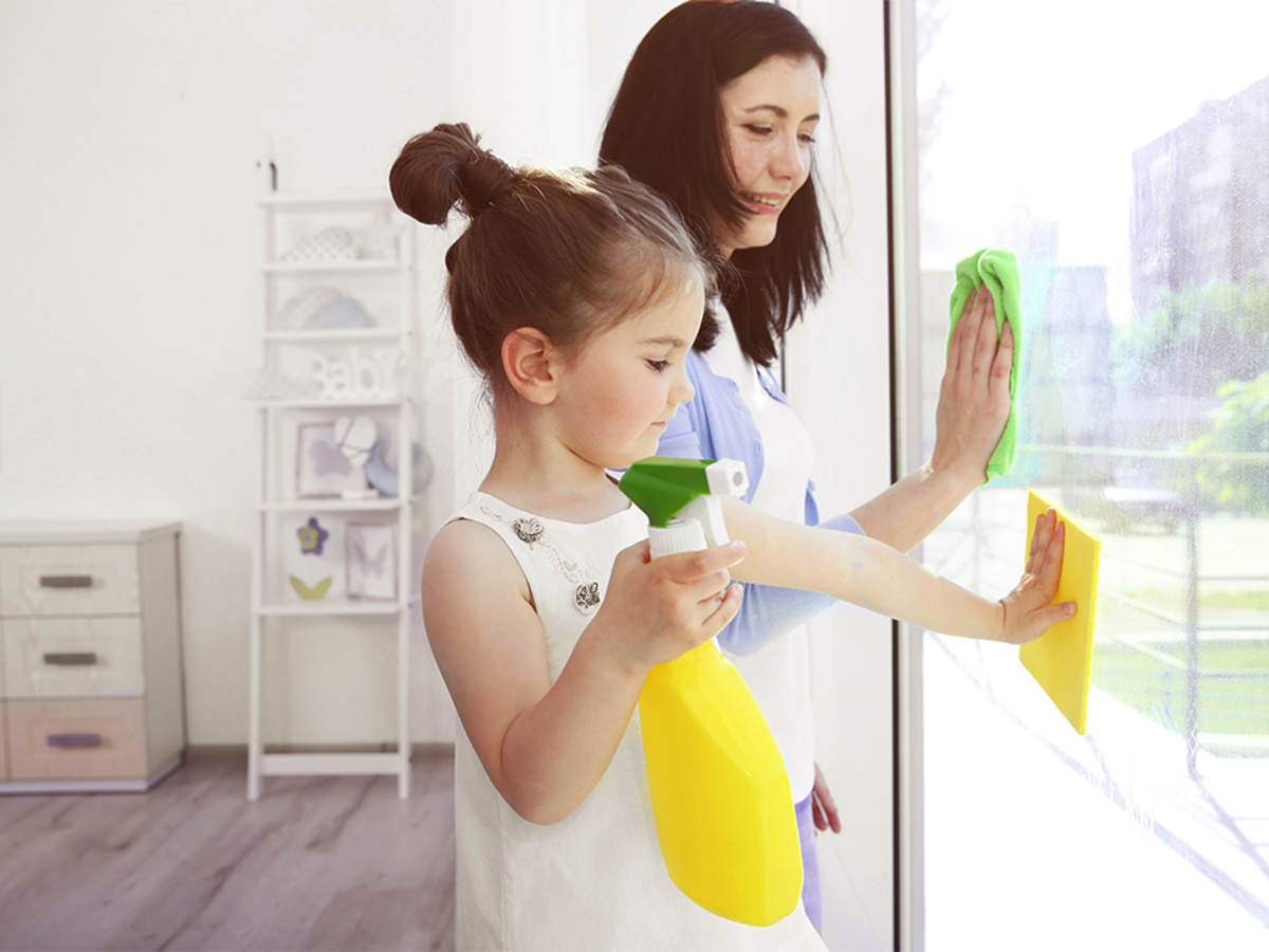 Girl helping her mother clean windows