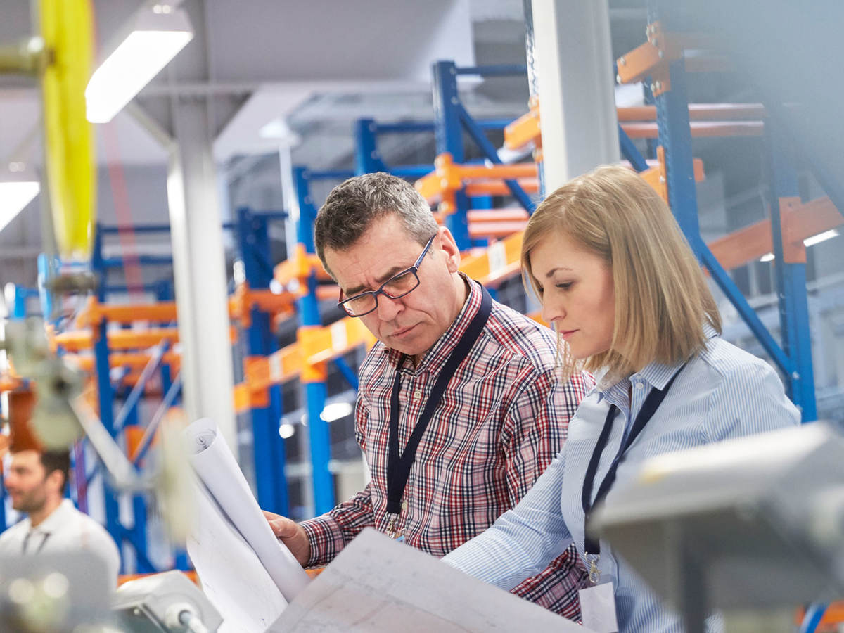 Two people at work looking at printed plans