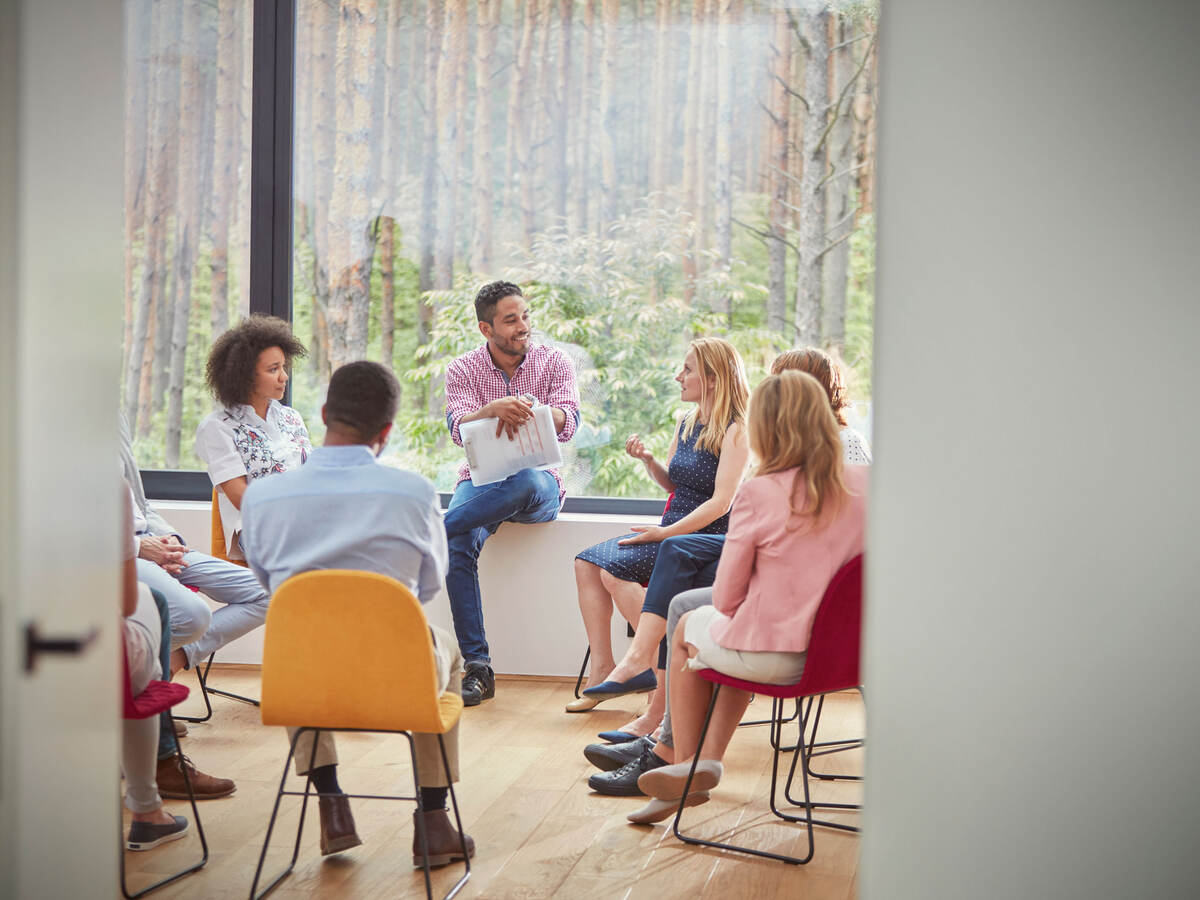 Group of people in an office space sitting in a circle for a meeting