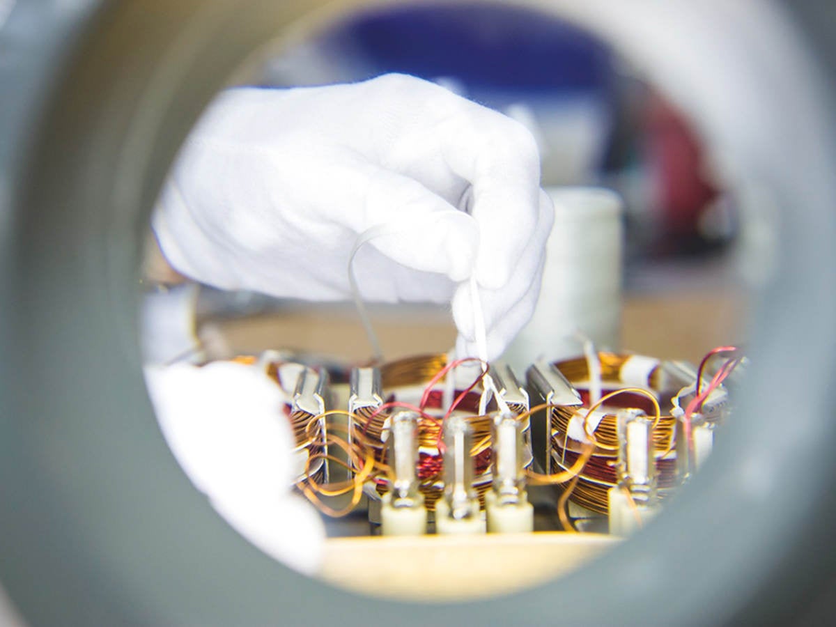 A close-up image of a gloved hand connecting wires in a laboratory setting. 