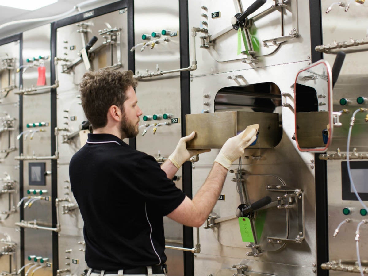 Man using a bank of small testing chambers to determine VOC emissions from products.