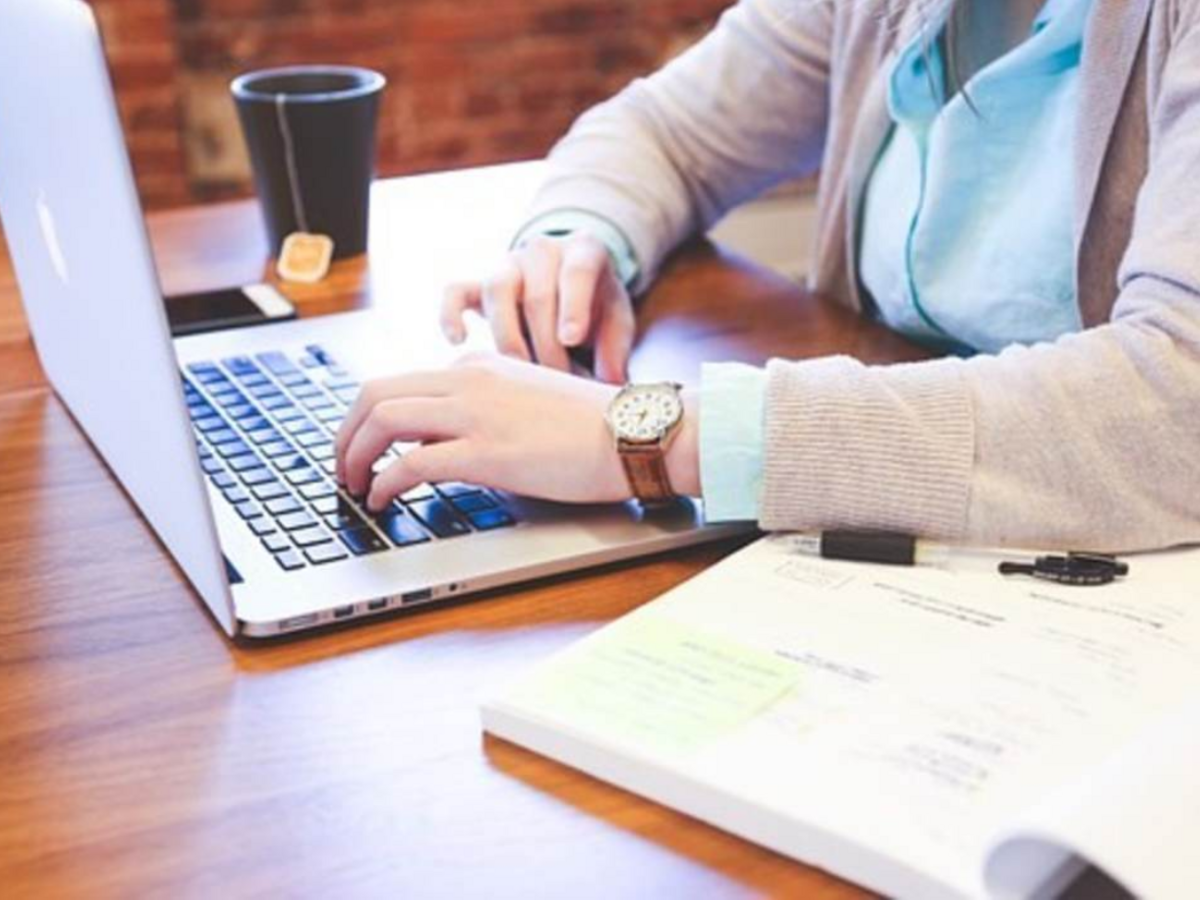 A person sustains her search for information on her laptop, comforted by her cup of hot tea.