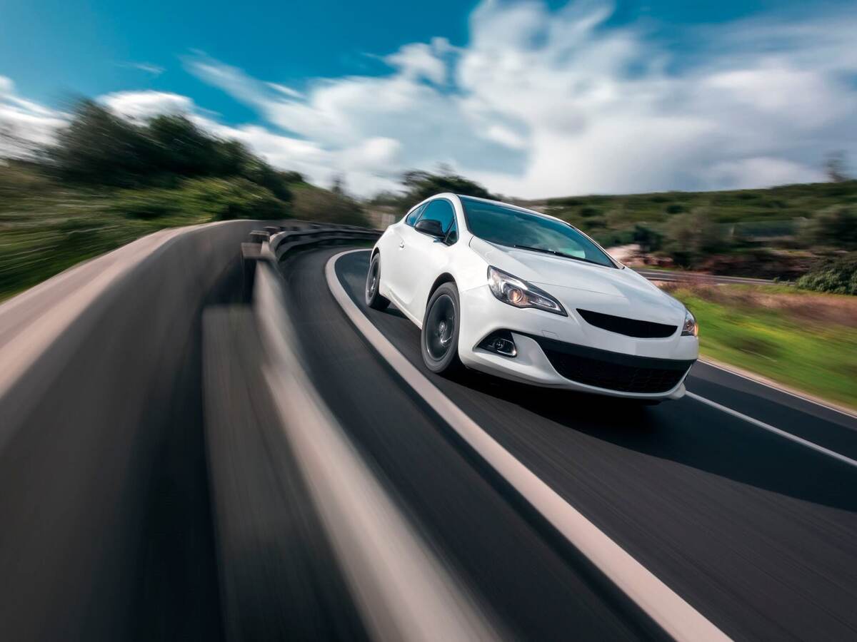 White car cornering in mountain road with speed blur